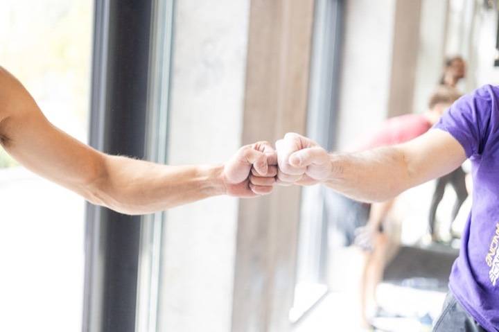 Ambiance conviviale et familiale à L'Atelier du Combat, Seichamps : check de poings entre pratiquants en salle